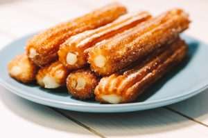 spanish sugar fritters served on blue dish on a wooden table