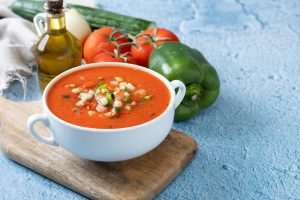 Traditional Spanish gazpacho soup in bowl on blue background